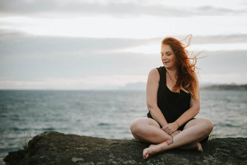 femme assise en tailleur sur un rocher au Bord de la mer