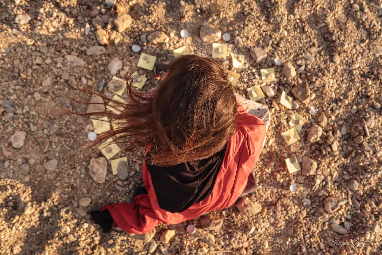 femme vue d'en haut assise dans le sable avec des post-it