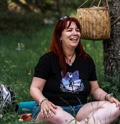 femme assise en tailleur dans l'herbe qui rigole