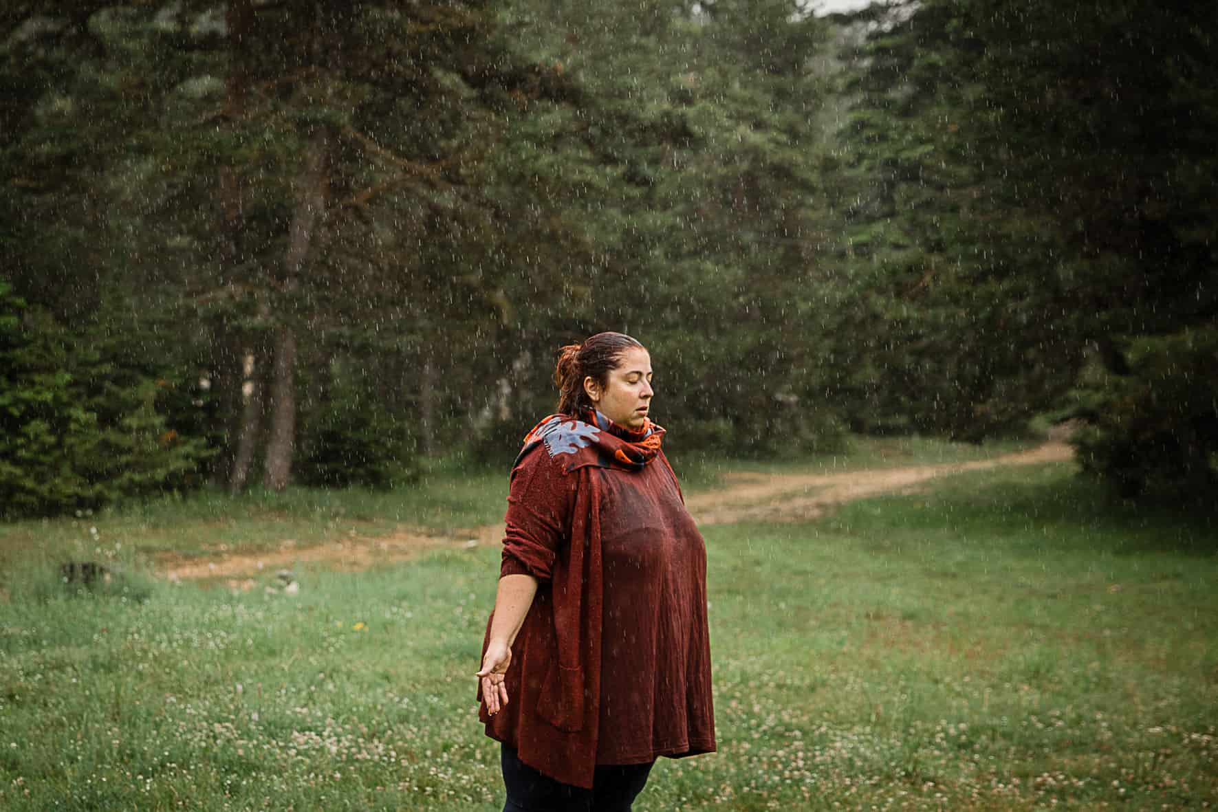 femme debout sous la pluie qui ferme les yeux