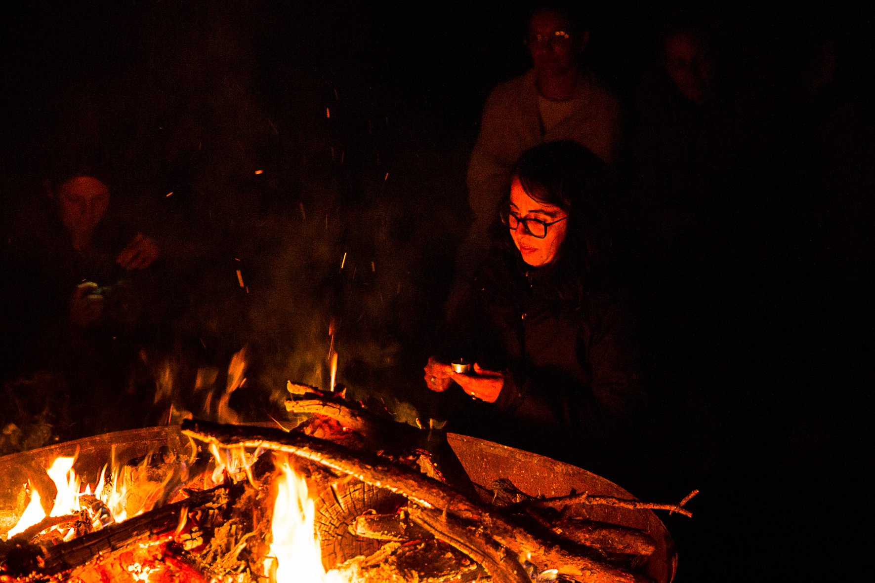 une femme accroupi au tour d'un feu pendant une retraite spirituelle