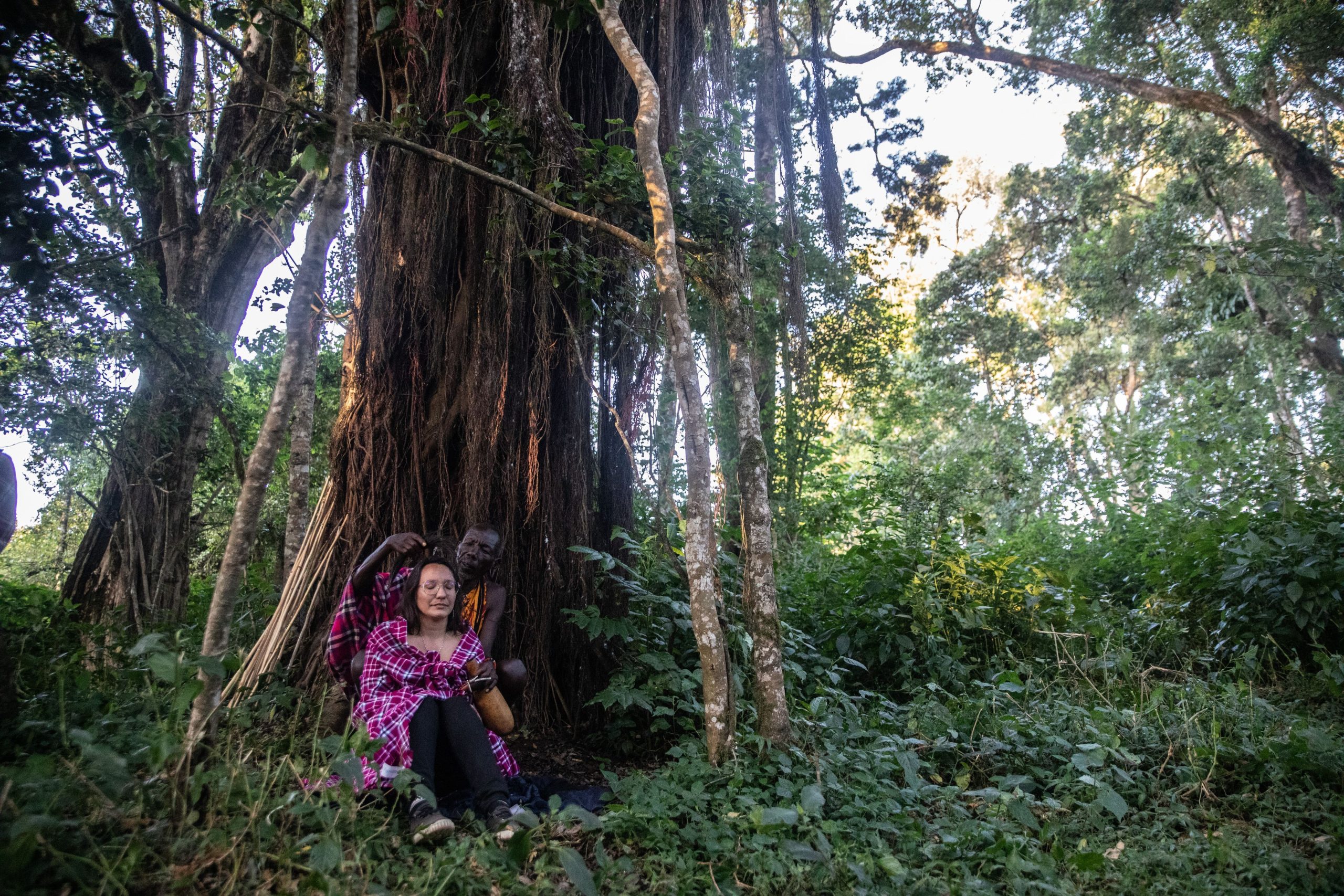 Participant lors de la retraite spirituelle Human au Kenya, en immersion culturelle Maasaï, assis sous un arbre sacré.