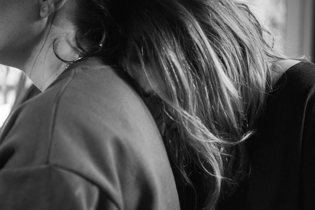 Une femme reposant sa tête sur une autre femme, illustrant un instant de libération émotionnelle et de résilience partagée.