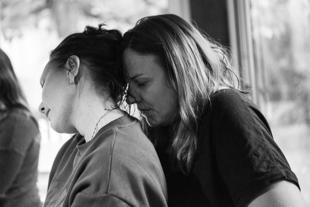 Deux femmes appuyées l'une contre l'autre, exprimant un moment d'émotion intense et de connexion humaine, symbolisant le soutien et la vulnérabilité dans la libération émotionnelle 