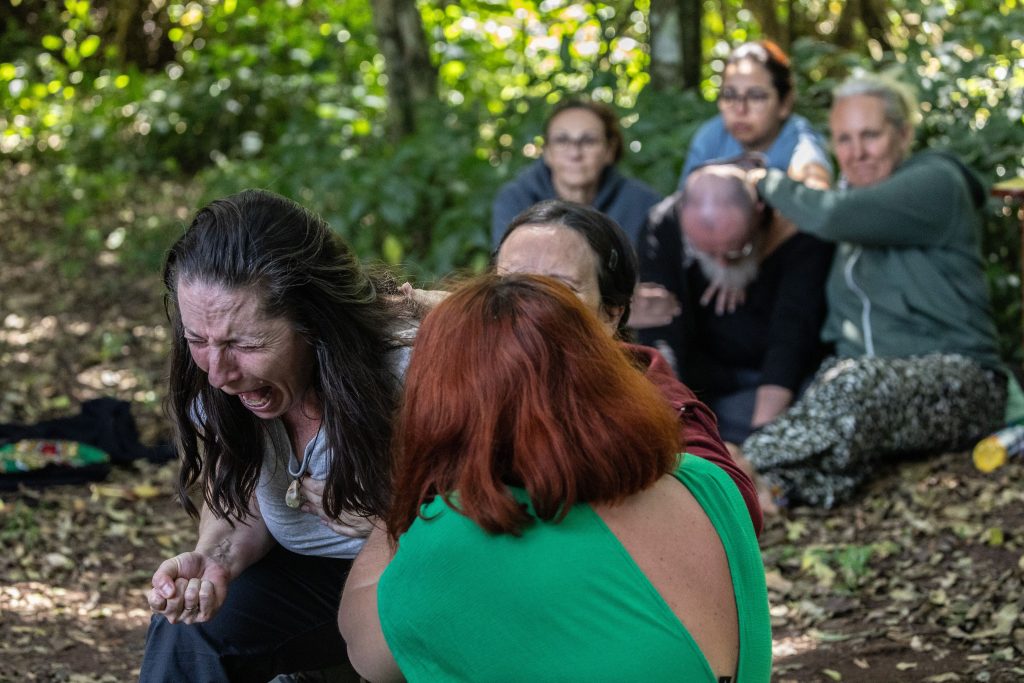 Groupe d'hommes en cercle, concentrés et engagés dans une retraite spirituelle axée sur le développement personnel chez l'homme, entourés par la nature.
