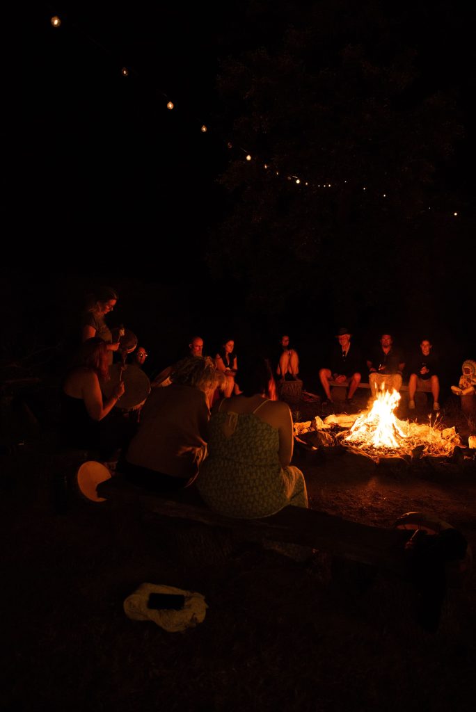 Cercle de partage autour du feu lors d'une retraite spirituelle, illustrant le développement personnel chez l'homme dans un cadre naturel et apaisant.