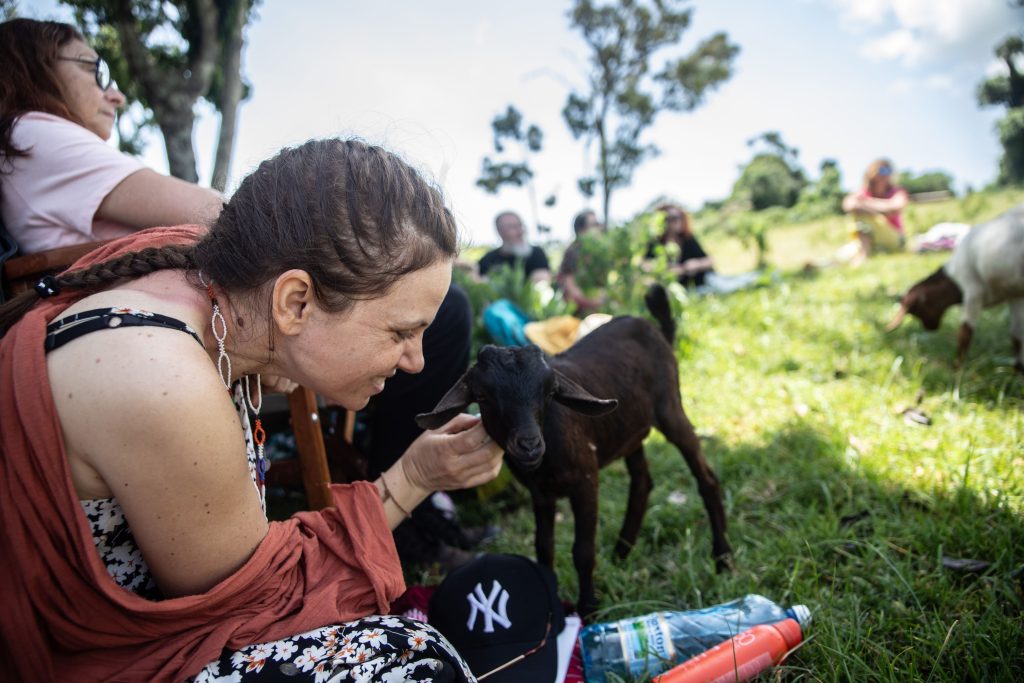Rencontre émouvante entre une participante et une chèvre en pleine nature, illustrant la douceur et la simplicité des moments vécus en retraite.