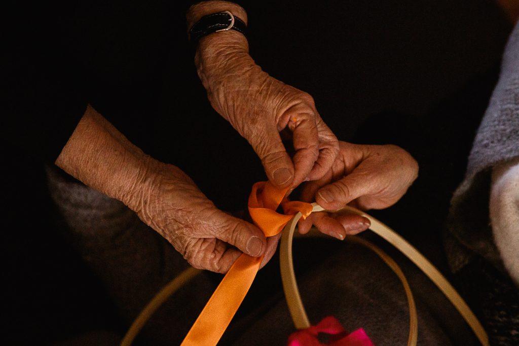 Mains entrelacées nouant un ruban, symbole de transmission et de lien intergénérationnel lors de la retraite famille.