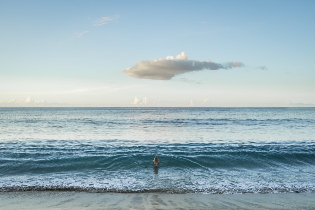 Femme face à l'immensité de l'océan au lever du soleil pendant une retraite thérapeutique en Guadeloupe
