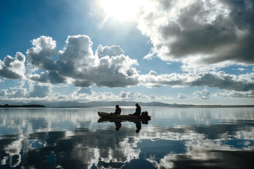 Deux participants en kayak sur une mer miroir, symbole d’équilibre entre féminin et masculin durant une retraite thérapeutique en Guadeloupe
