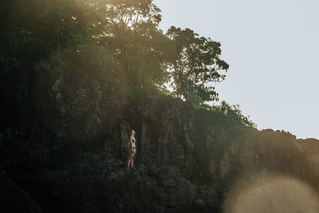 Femme debout en maillot face à une falaise, moment de courage et de choix de liberté pendant une retraite en Guadeloupe