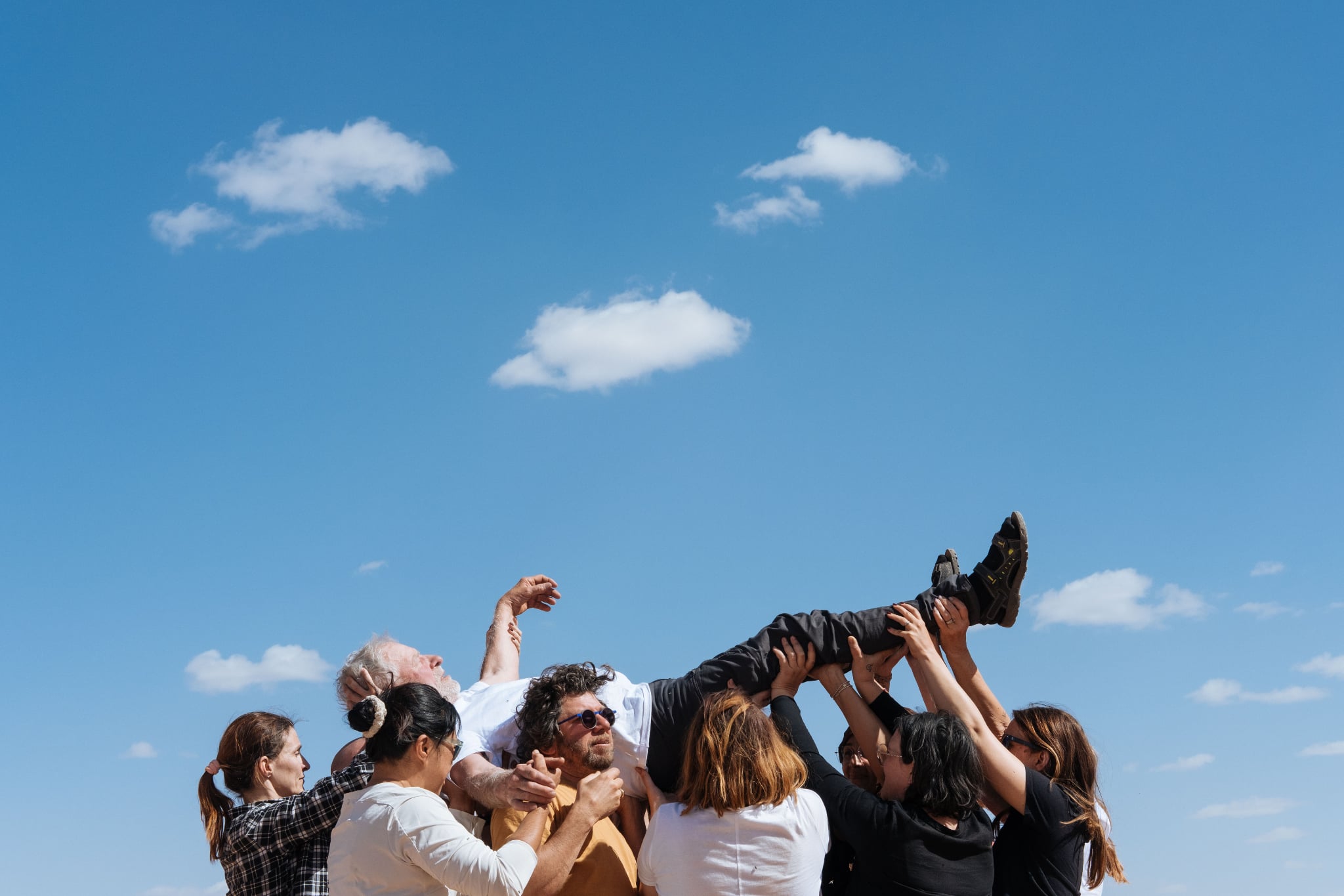 Un groupe de participants soulève un homme lors d’un atelier de confiance pendant une retraite, symbole de soutien et de communication authentique.