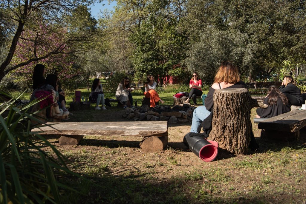 Cercle de femmes en rituel autour d’un feu sacré pendant une retraite thérapeutique, moment de libération et de sororité puissante.