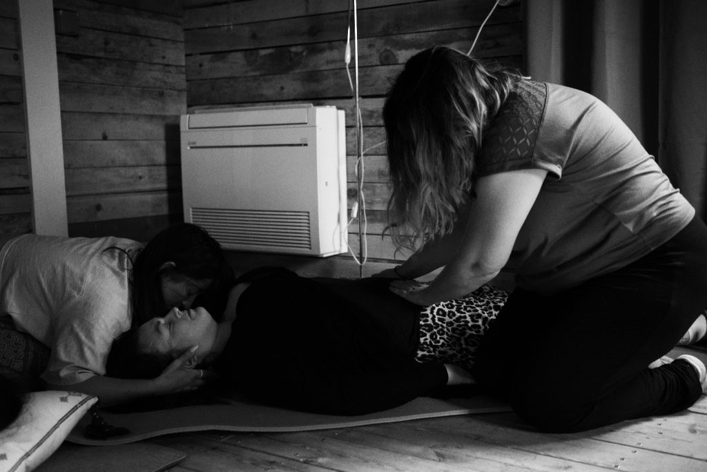 Femme accompagnée avec douceur et présence pendant un soin émotionnel profond lors d’une retraite thérapeutique entre femmes.