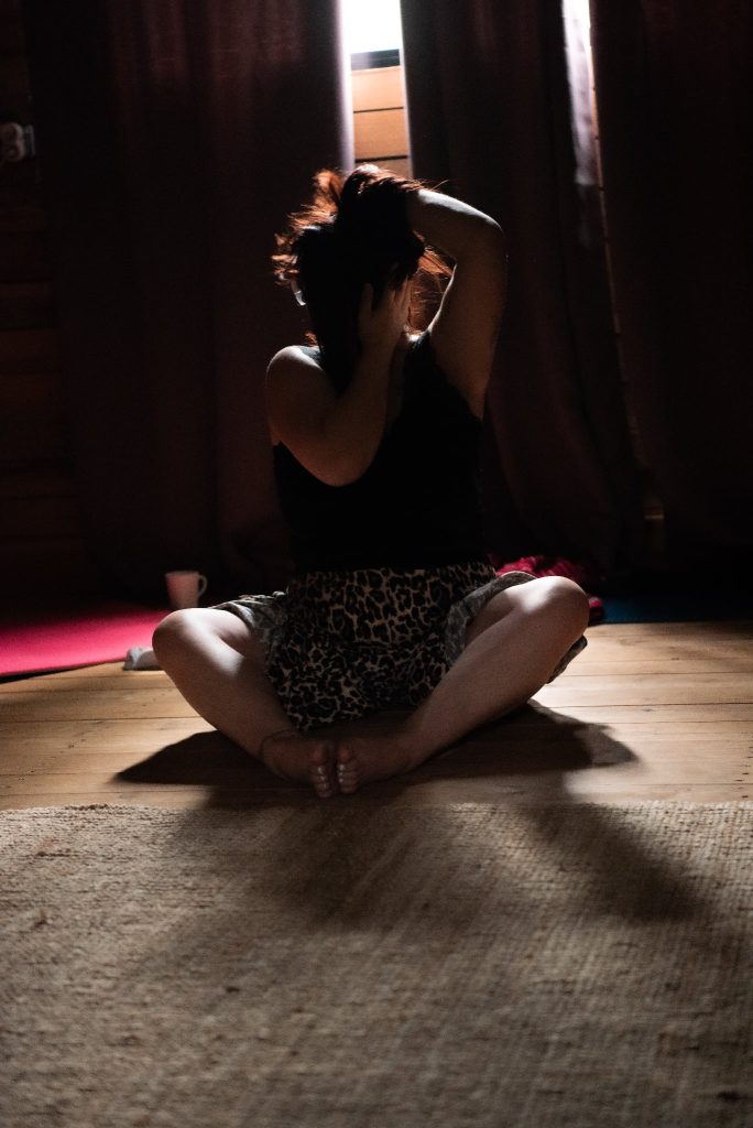Femme en pleine exploration corporelle et sensorielle dans un espace intime et sécurisé lors d’une retraite thérapeutique entre femmes.