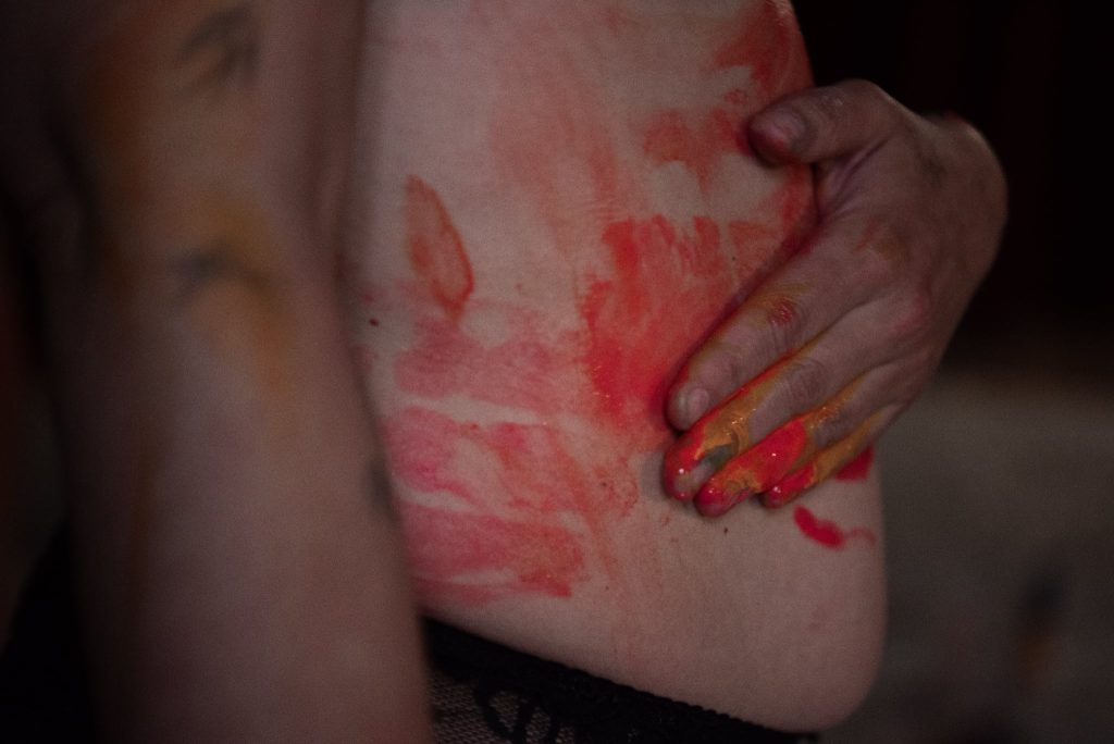 Main de femme recouverte de peinture sur son ventre dans un atelier de reconnexion à soi, vécu fort d’une retraite thérapeutique entre femmes.