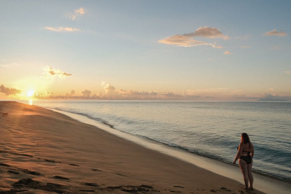 
Femme marchant au bord de la plage au coucher du soleil, symbole de liberté intérieure et de connexion à soi.
