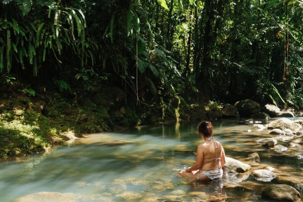 Femme méditant dans une rivière au cœur de la nature, expérience de liberté intérieure et de paix profonde.