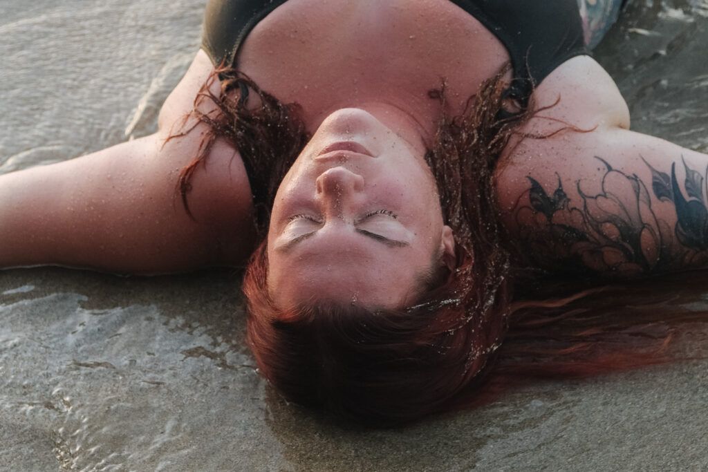 Aurélie allongée sur le sable, moment de libération et de lâcher-prise pendant une retraite spirituelle, témoignage de son chemin de développement personnel.