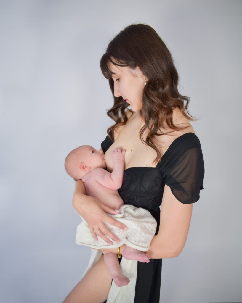 Tiffany, jeune maman et entrepreneur, allaite son bébé avec tendresse, symbole de la fusion entre maternité et reconnection à soi dans son parcours d’entrepreneure.