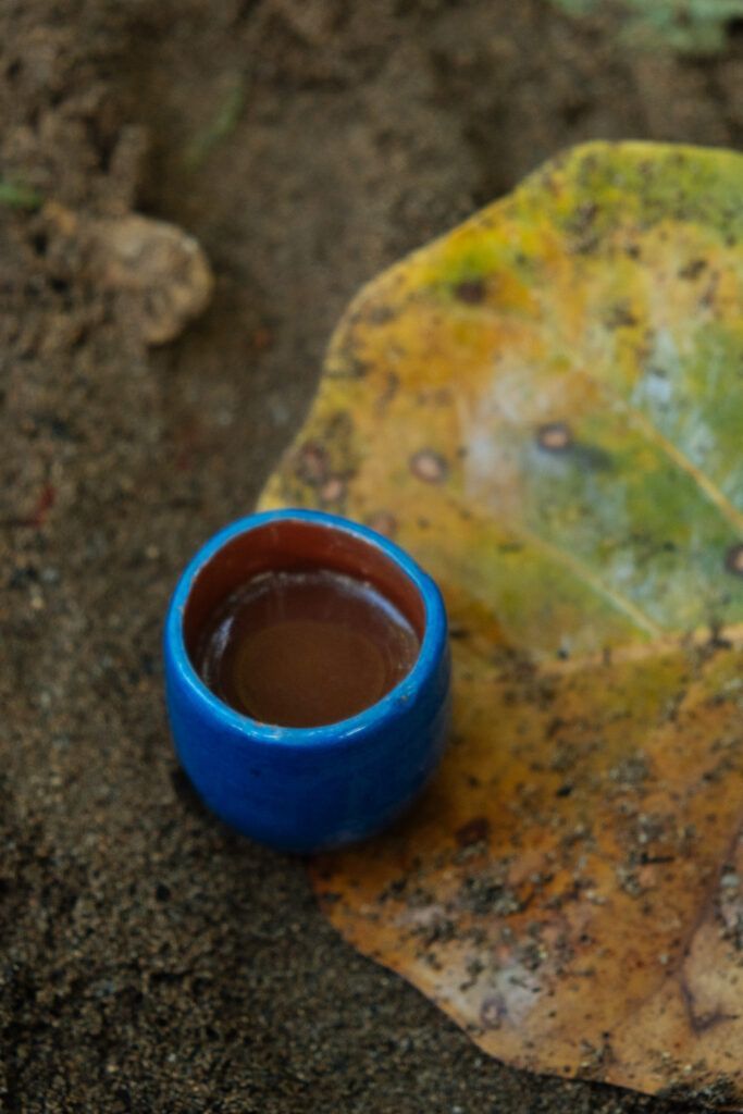Petit bol en terre utilisé lors d’un rituel de retraite féminin sacré Makaïa, posé sur le sable et une grande feuille, symbole de retour à la terre et du sacré dans les pratiques féminines.