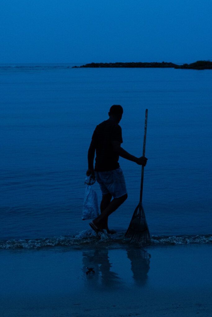 Quand la maladie entre dans une famille : ce que l’on ne voit presque jamais 3 Pêcheur marchant dans l’eau au crépuscule en Guadeloupe, évoquant les crabes des sables et la symbolique du cancer dans l’article quand la maladie entre dans une famille.