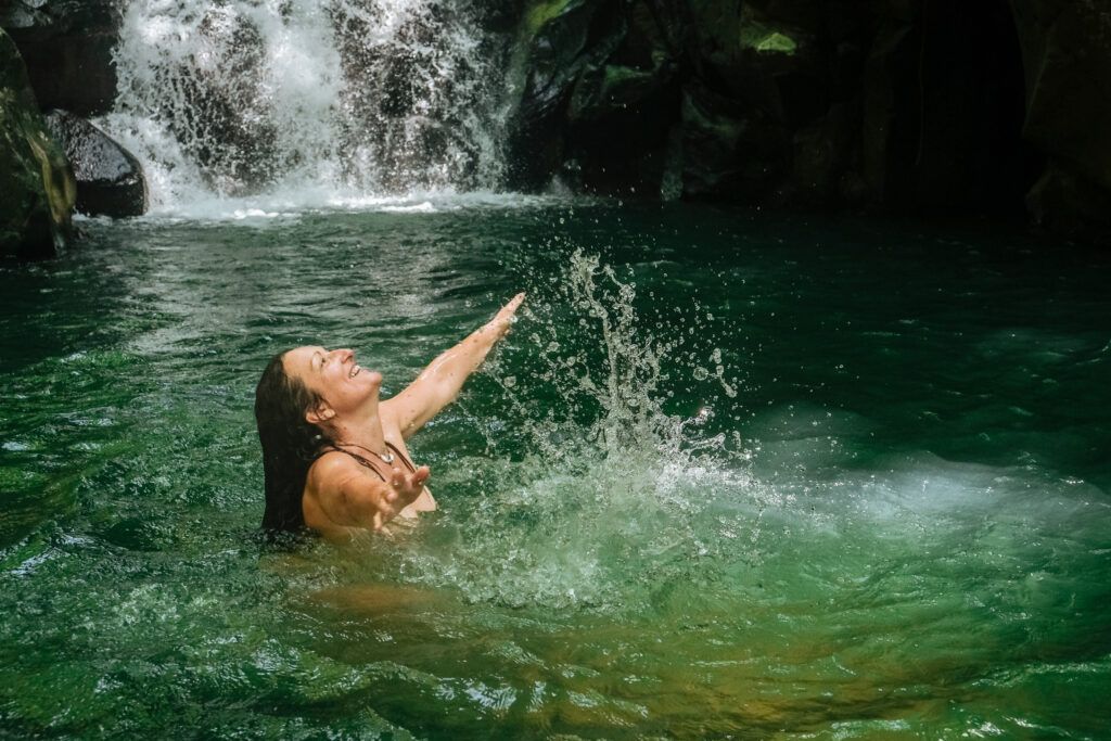 Femme dans l’eau bras ouverts exprimant la joie et la libération émotionnelle, symbole de la liberté personnelle incarnée