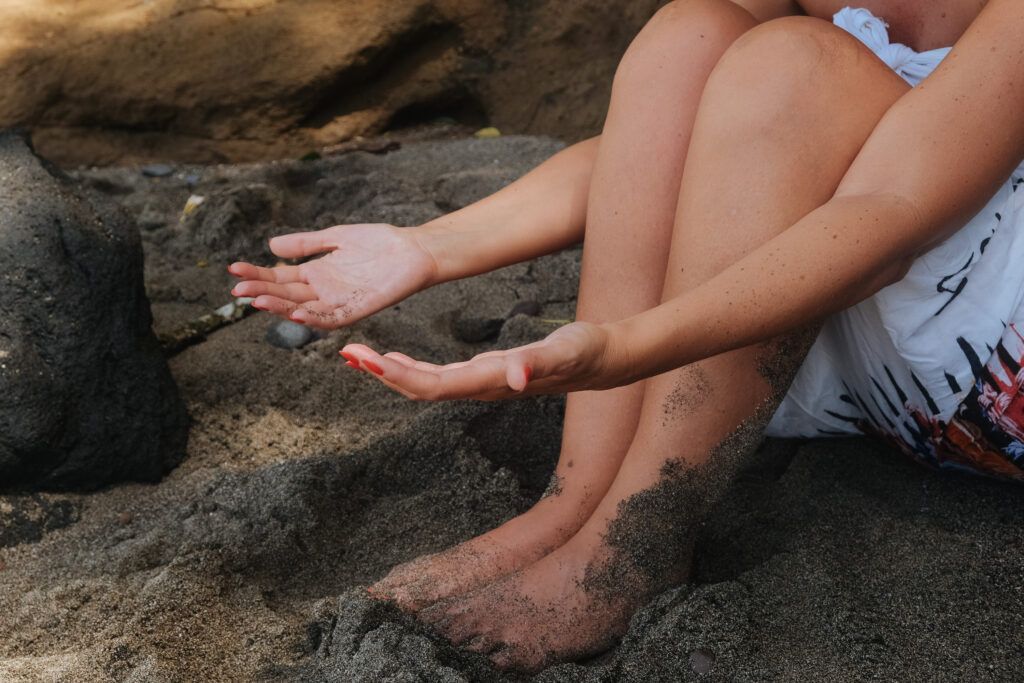 Mains ouvertes sur le sable, symbole d’ancrage, de présence à soi et de liberté personnelle dans le corps