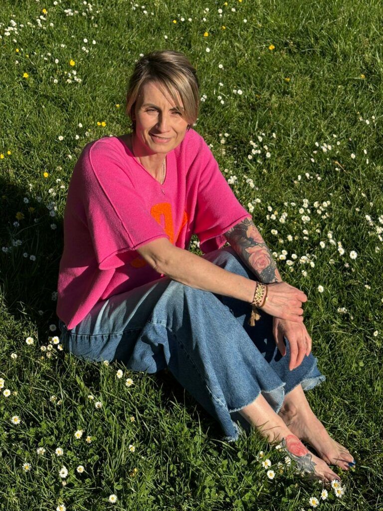 Confiance en soi et entrepreneuriat féminin : "Je suis la reine de ma vie" 2 Karine, thérapeute énergéticienne à Haguenau, assise dans une prairie de marguerites — confiance en soi et entrepreneuriat féminin