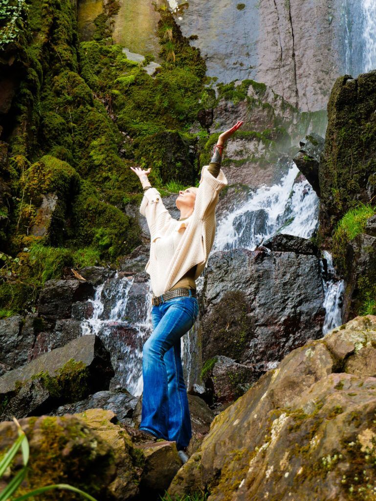 Confiance en soi et entrepreneuriat féminin : "Je suis la reine de ma vie" 4 Femme bras levés vers le ciel devant une cascade, symbole de liberté et de confiance en soi dans l'entrepreneuriat féminin