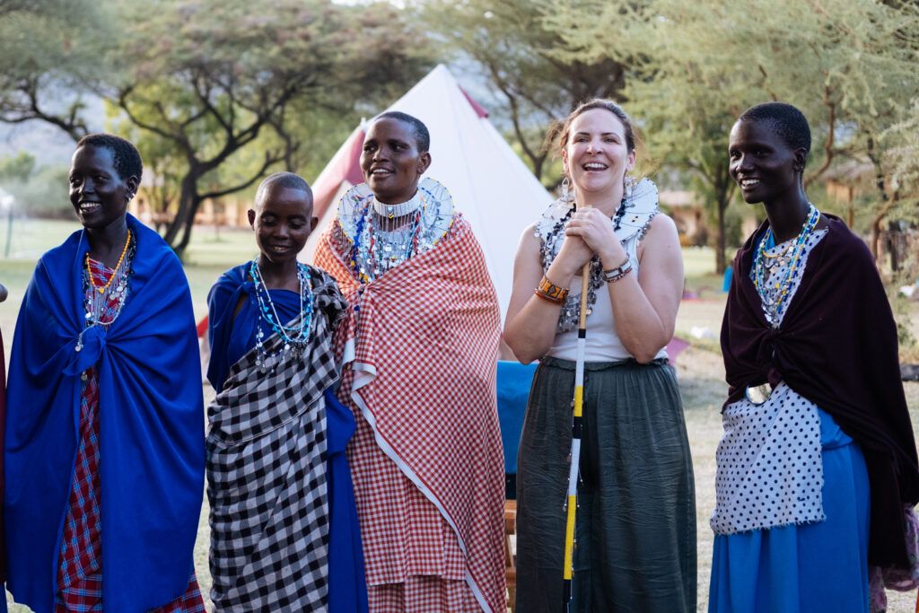 Voyage initiatique en Afrique : le témoignage de Cindy, partie seule se retrouver en Tanzanie 8 Participante de la retraite HUMAN rayonnante entourée de femmes Maasaï en tenue traditionnelle, voyage initiatique en Tanzanie
